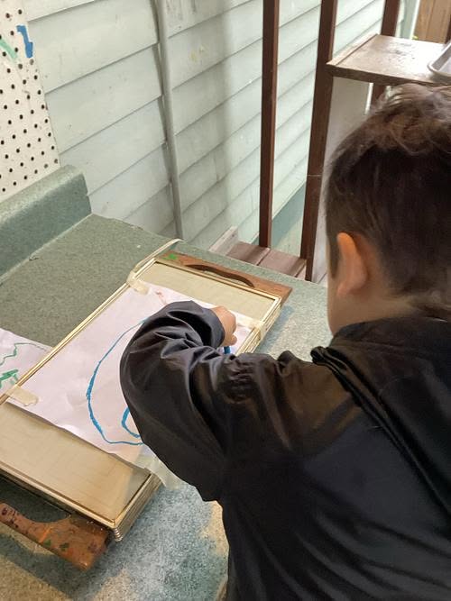 A child exploring melted crayon art on a warming surface